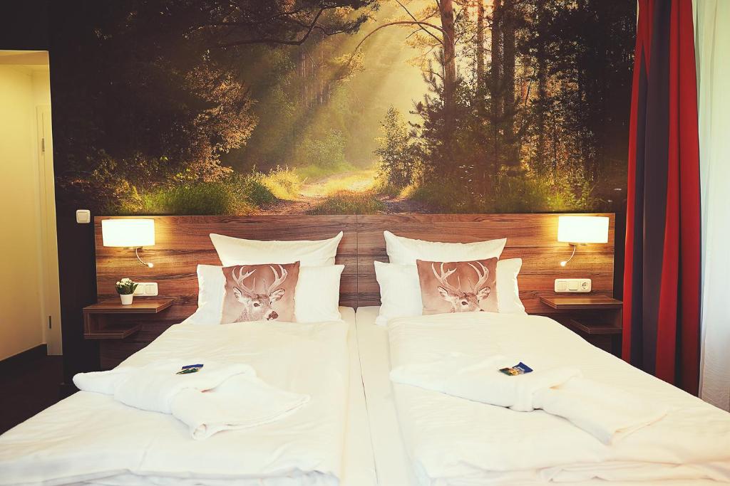 1 cama con sábanas blancas y almohadas con una pintura en Hotel Mein Bergblick, en Hahnenklee-Bockswiese