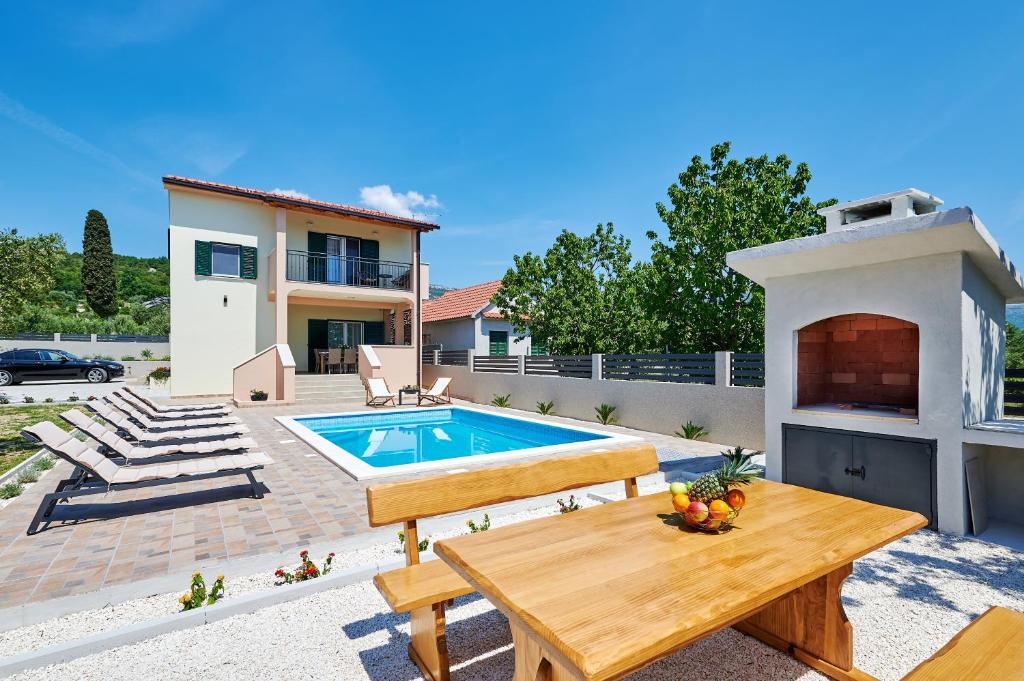 een achtertuin met een houten tafel en een zwembad bij Villa Lilly in Kaštel Novi