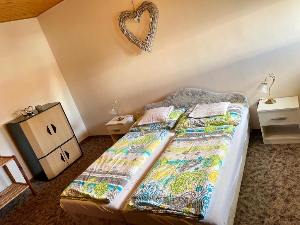 a bedroom with a bed with a heart on the wall at Esther Apartman in Gyenesdiás