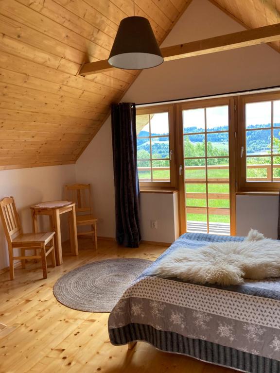 a bedroom with a bed and a table and windows at Ciche Pole in Maniowy