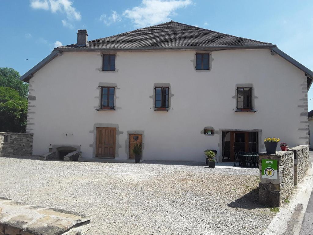 a white house with black windows and a gravel driveway at Gite de la Diligence in Le Fied