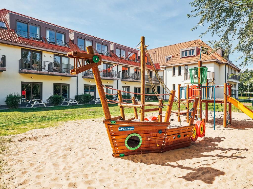 a playground in the sand in front of a building at Holiday Suites Westende in Westende