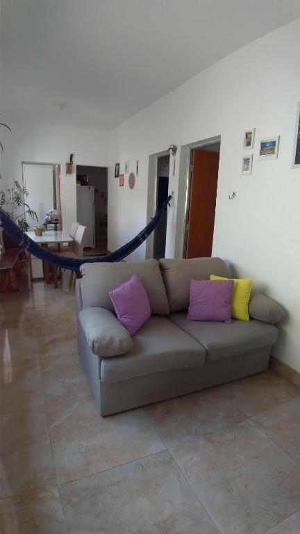 een woonkamer met een bank met paarse en gele kussens bij Hostel Miscelânea in Sete Lagoas