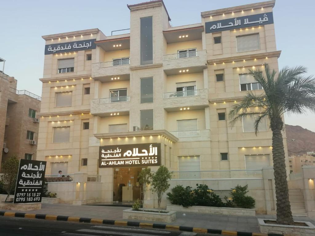 a building with a palm tree in front of it at Al-Ahlam Hotel Apartments in Aqaba