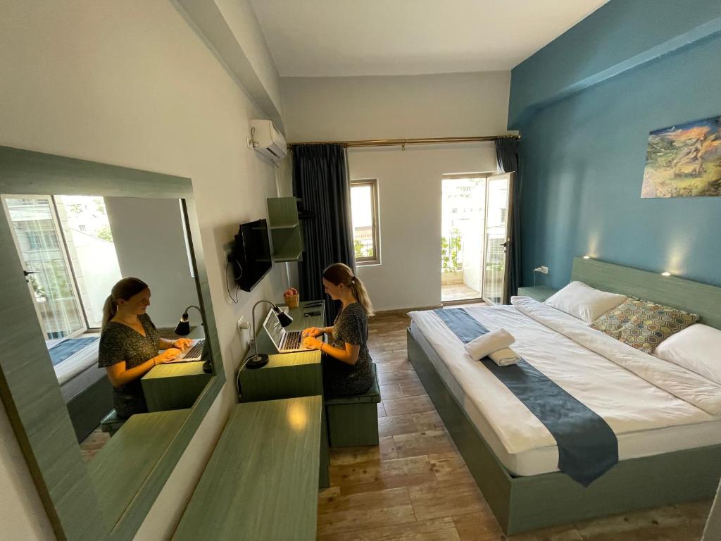 Dos mujeres en una habitación de hotel con cama y espejo en The Sydney Hotel, en Amán