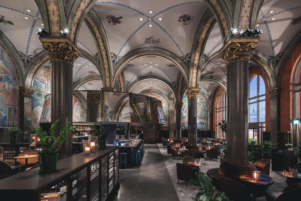 un restaurant avec des plafonds ornés, des tables et des chaises dans l'établissement Bergen Børs Hotel, à Bergen