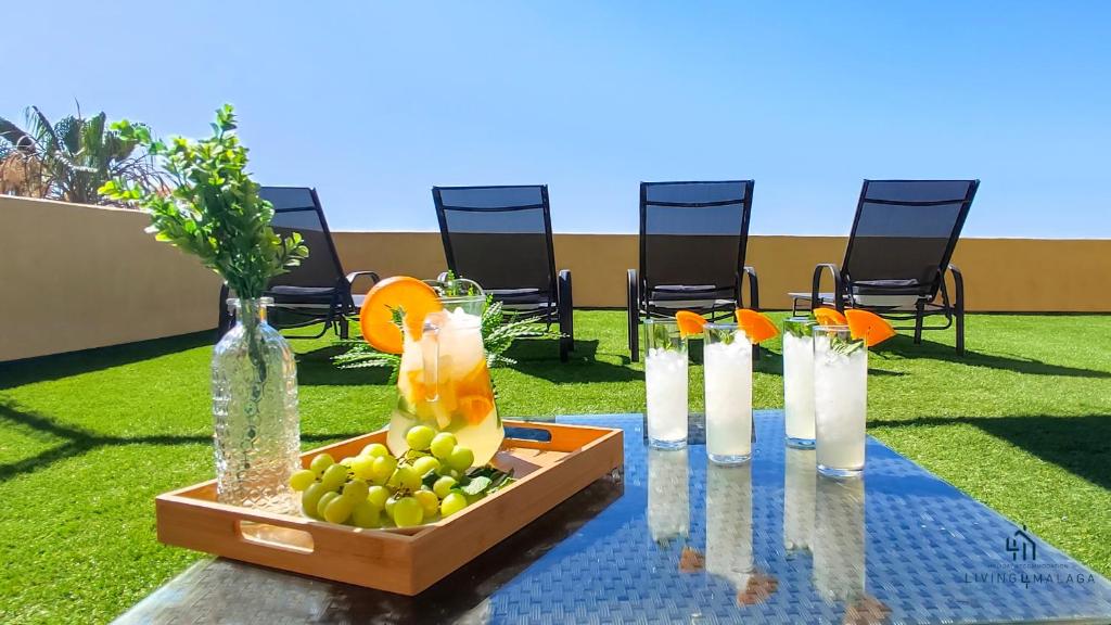 una mesa con una bandeja de fruta y botellas de agua en Living4Malaga Monte Sancha Deluxe View, en Málaga