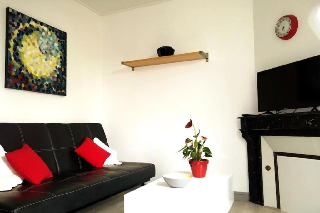 a living room with a black couch and a fireplace at Entre ville et jardins in Sainte-Savine