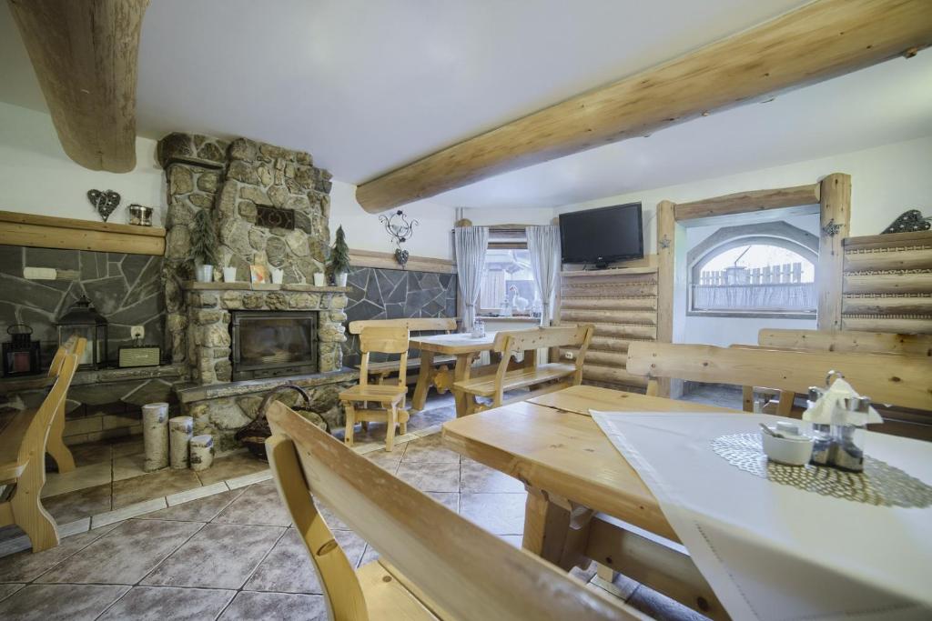 una sala de estar con mesas de madera y una chimenea de piedra. en Willa Bartuś Baliczek en Bukowina Tatrzańska