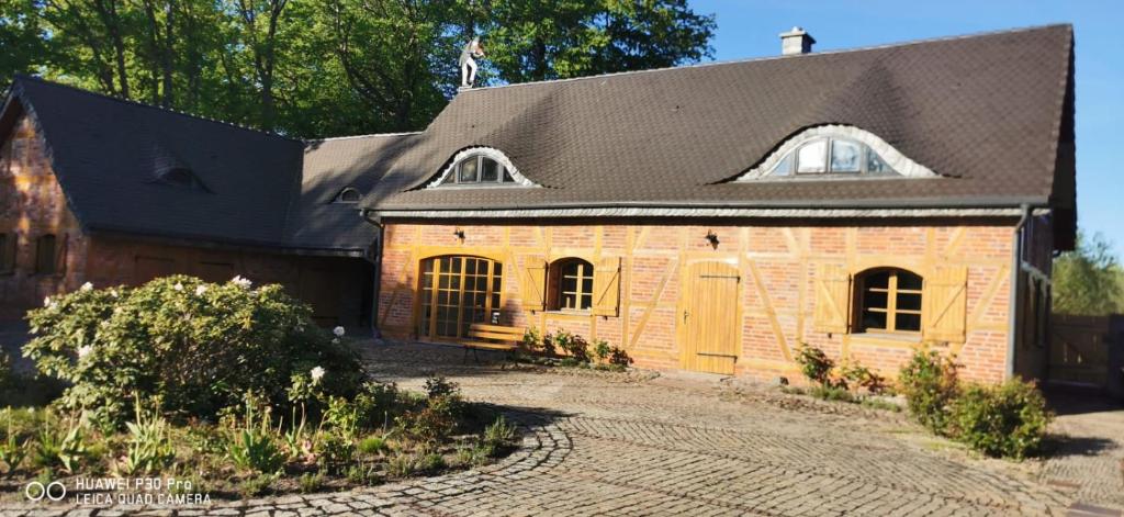 a brick house with a black roof and a driveway at Violin house in Strzelinko