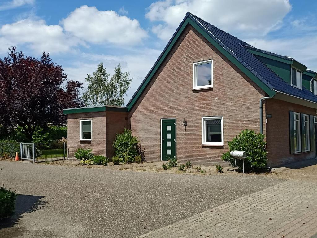 a brick house with a green door on a street at Vakantiehuis Mastdreef in Breda