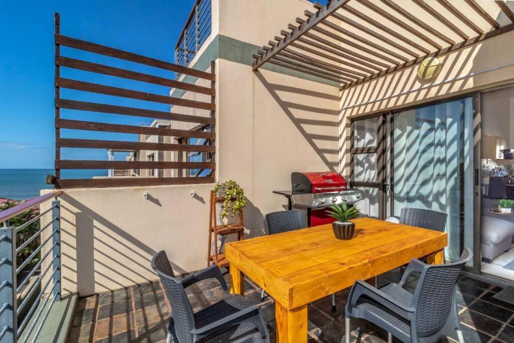 a wooden table and chairs on a balcony at Cozy All-in-One Ocean View Apartment in Kingsborough