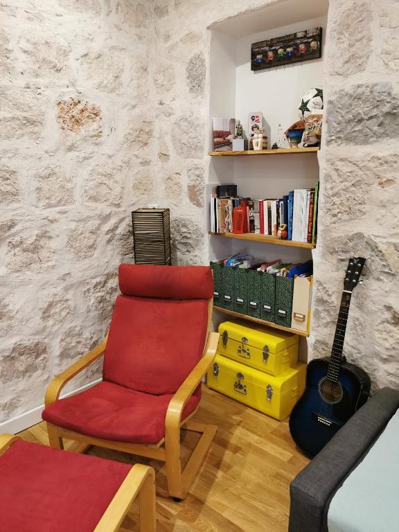 - un salon avec une chaise rouge et une guitare dans l'établissement Our home, Cozy Apartment two minutes from the sea - Clima, à Nice