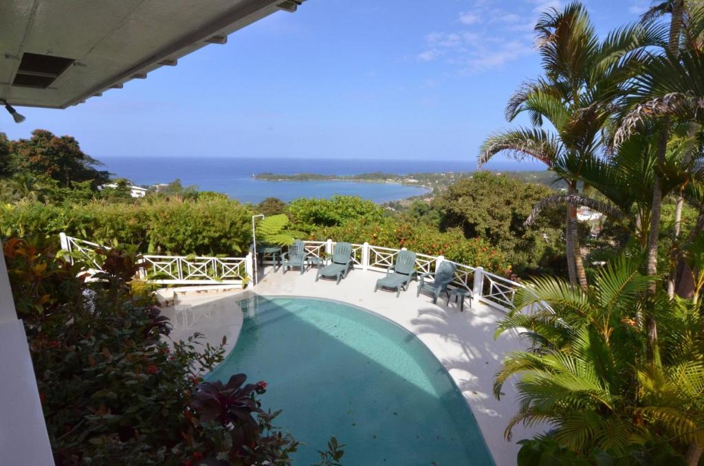 a swimming pool with chairs and a view of the ocean at Tranquility Villa in Port Antonio