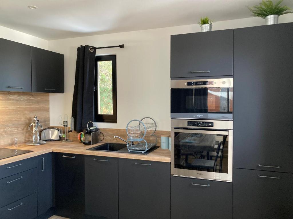 kuchnia z czarnymi szafkami i piekarnikiem w obiekcie Chez Marie-Pierre w mieście Les Angles