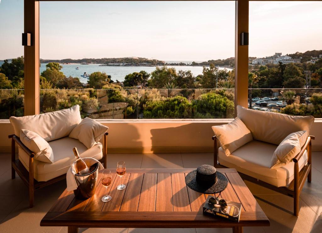 een woonkamer met een tafel en stoelen en een groot raam bij Somewhere Vouliagmeni in Athene