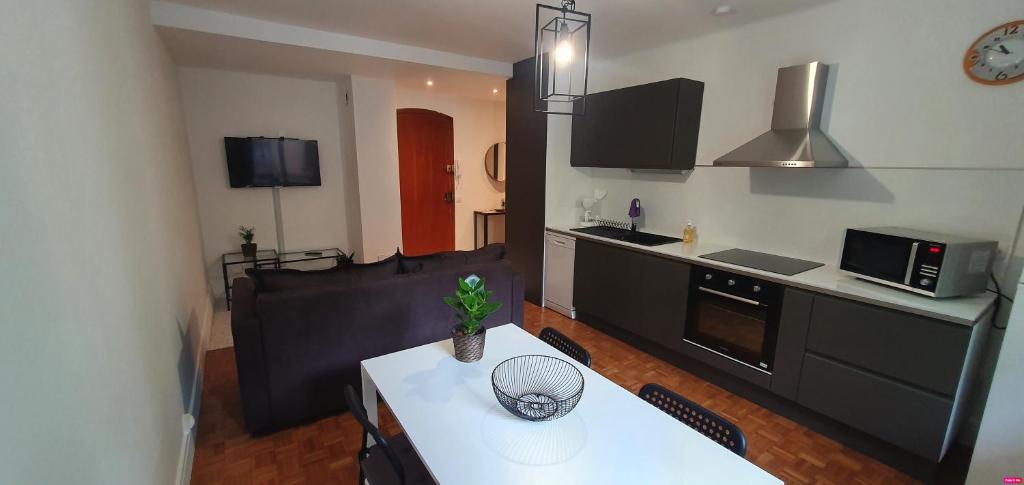 a living room with a white table and a kitchen at Joli F2 neuf tout équipé proche centre Annecy et Gare in Annecy