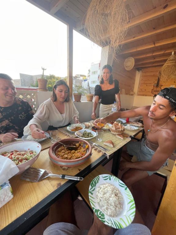Un groupe de personnes assises autour d'une table et mangeant de la nourriture dans l'établissement We surf Morocco BOUTIQUE HOUSE, à Taghazout