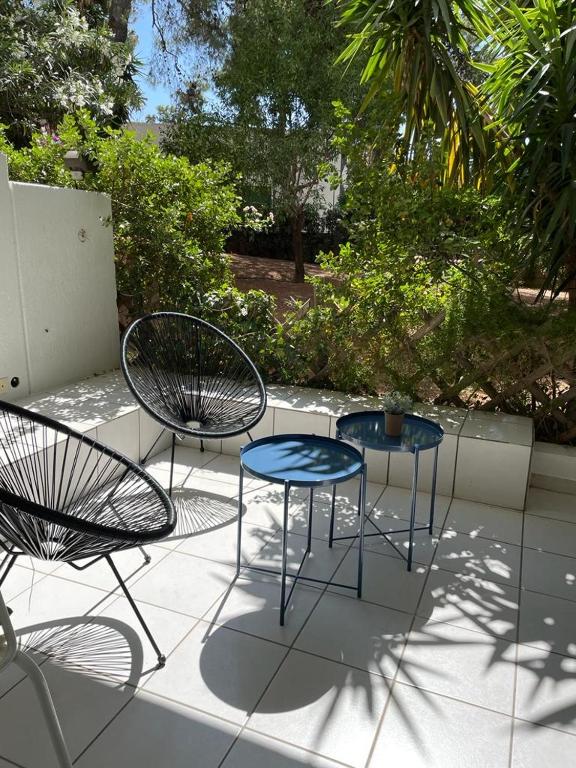 dwa krzesła i dwa stoły na patio w obiekcie Vouliagmeni‘s Secret Garden near the Sea w Atenach
