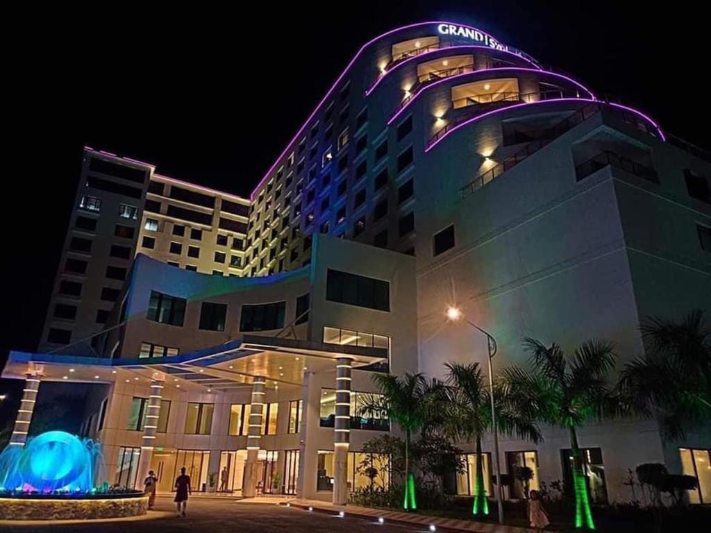 Grand Sylhet Hotel & Resort في سيلهيت: مبنى كبير مع مبنى مضاء في الليل