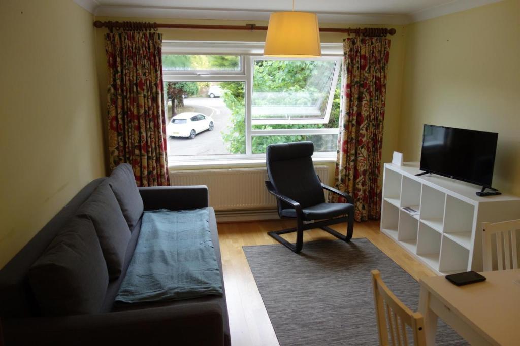 a living room with a couch and a chair and a window at NEW Cosy 2 Bedroom Flat - Englefield Green in Englefield Green