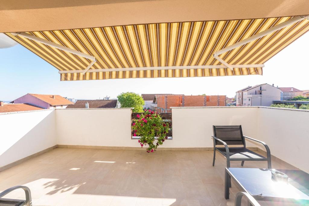 a balcony with a wooden roof with chairs and a table at Apartments Maza in Zadar