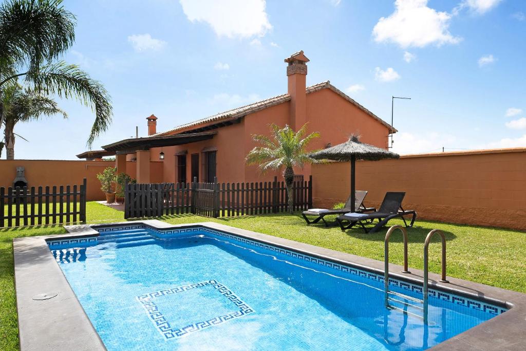 - une piscine en face d'une maison dans l'établissement Villa Marta Clara 2, à Conil de la Frontera