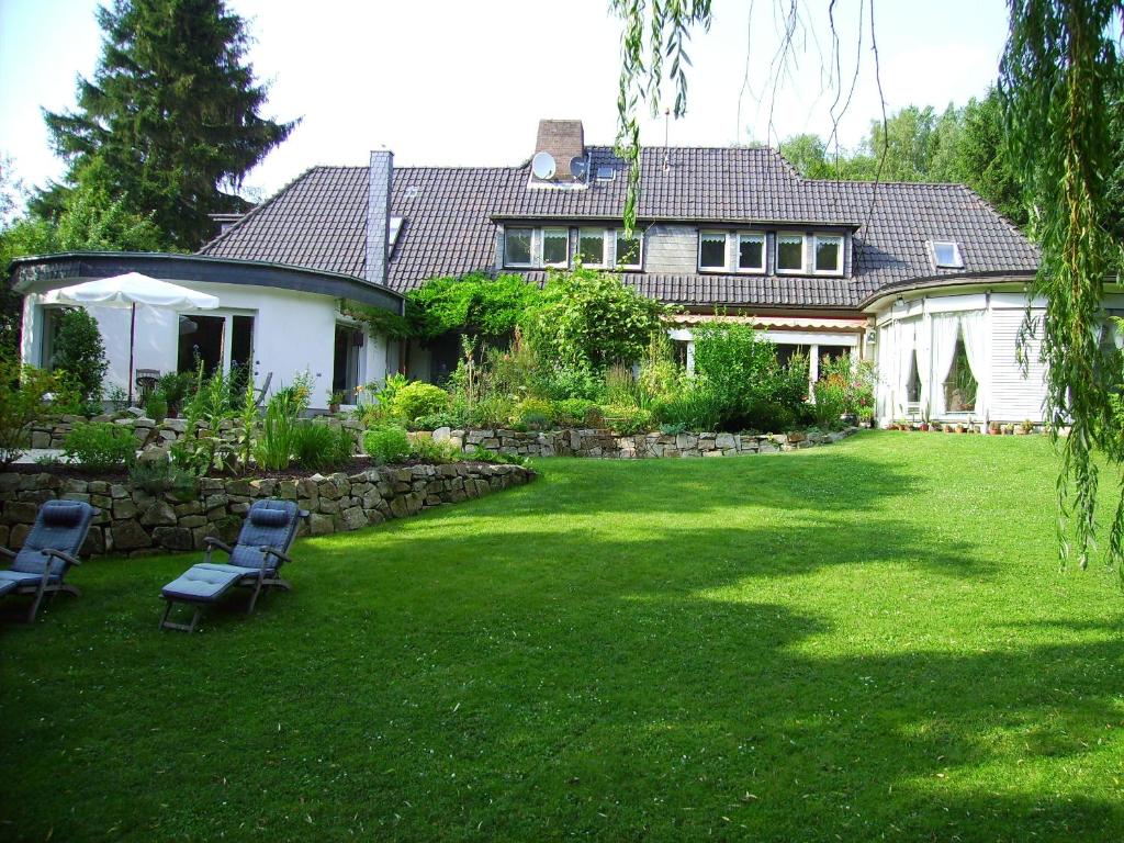 ein Haus mit einem Hof mit zwei Stühlen im Gras in der Unterkunft Gästehaus Villa Kreativ Susanne Lay in Bad Münder am Deister