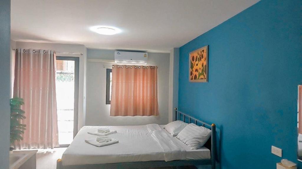 OYO 75403 Dinosaur Apartment في هوا هين: غرفة بسرير مع جدار ازرق