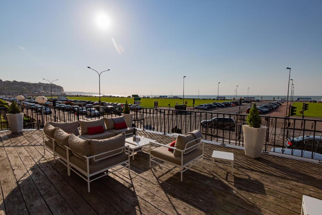 uma varanda com sofás e mesas e um parque de estacionamento em Hotel Aguado em Dieppe