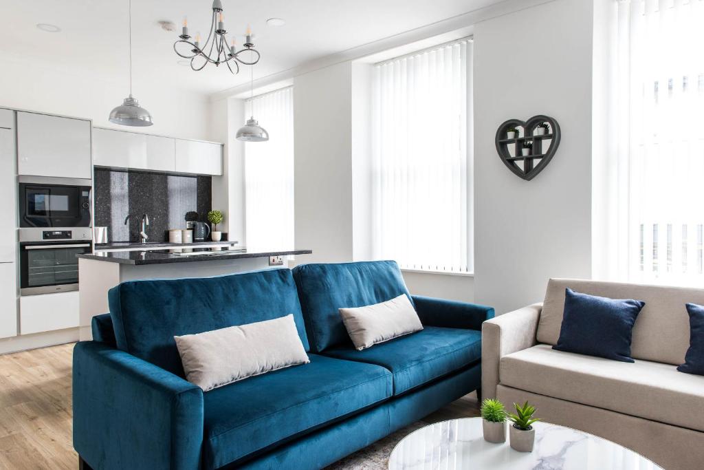 a living room with a blue couch and a chair at Osprey Residence - Smart & Stylish Apartment in the Heart of Kendal in Kendal