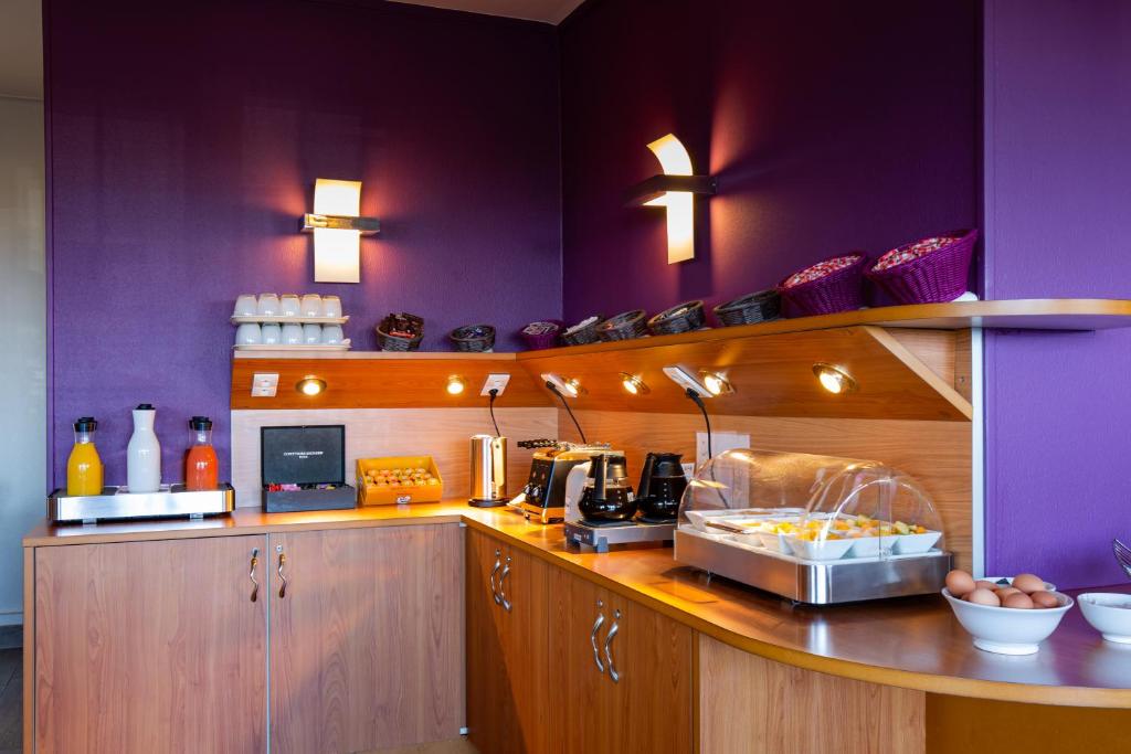 a kitchen with purple walls and a counter with food at Hotel Aguado in Dieppe