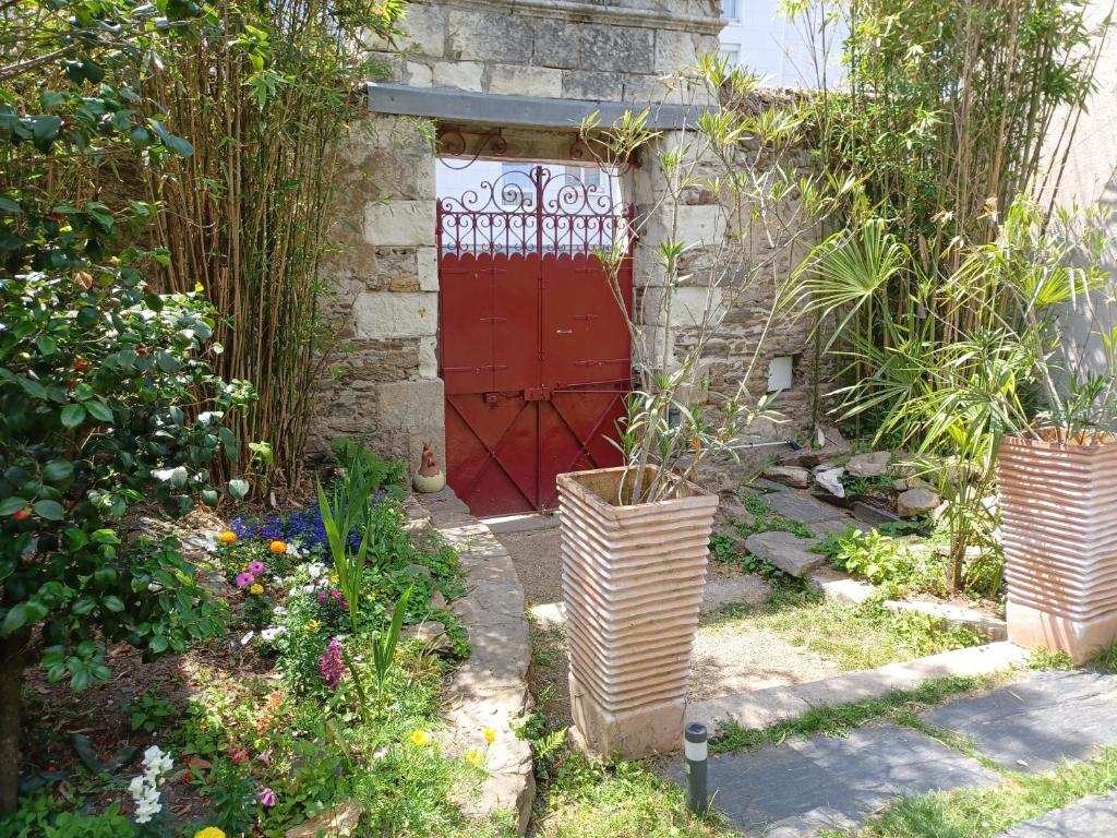 Le pigeonnier de la plume في نانت: باب احمر في حديقة بها بعض النباتات