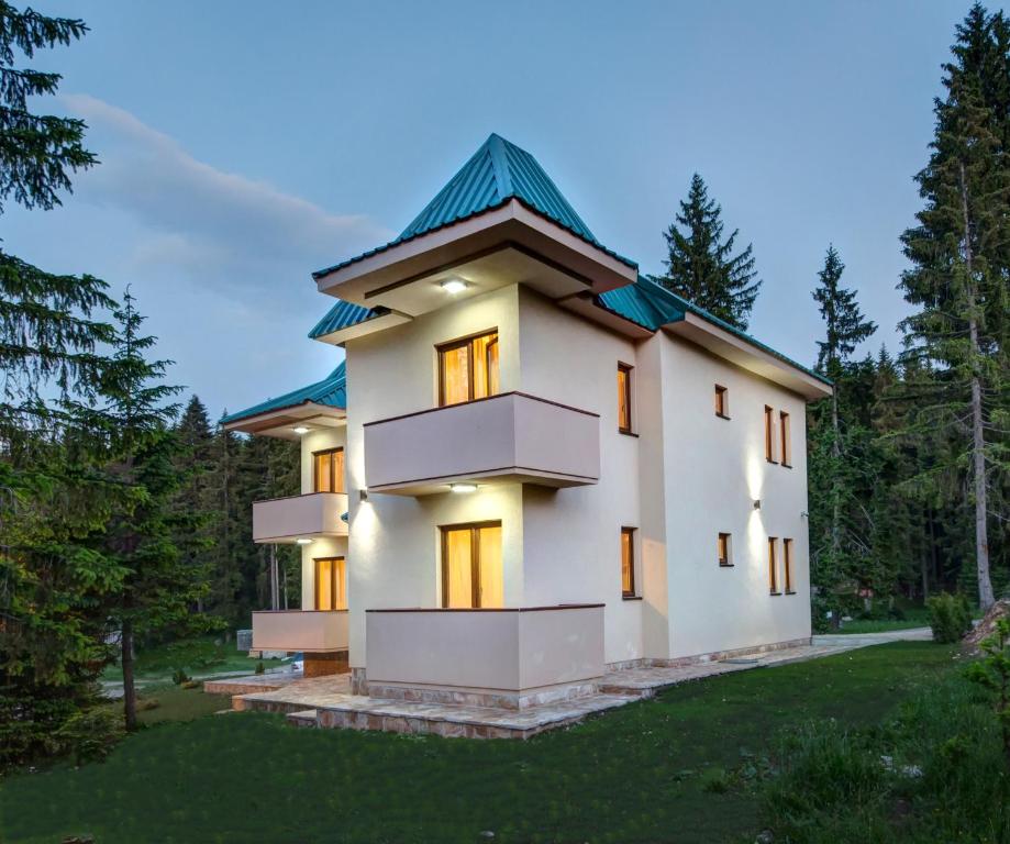 una grande casa bianca con tetto verde di Apartmani Bijelic a Žabljak
