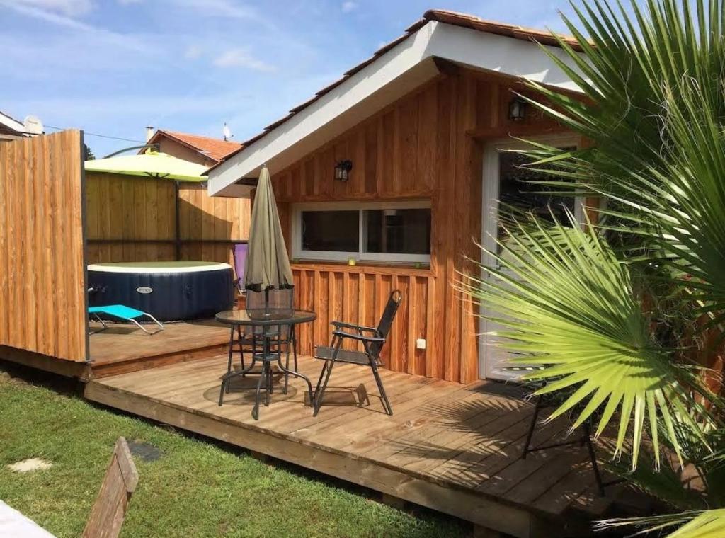a wooden deck with a table and chairs on it at Adorable chalet des Huttiers - Bassin d'Arcachon in Audenge