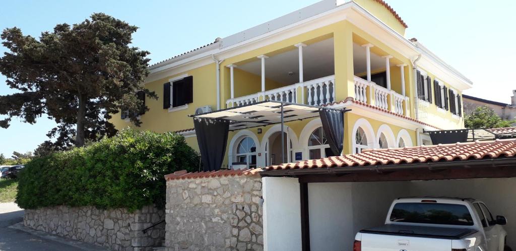 uma casa amarela com um camião branco estacionado em frente em Vivi studio apartments em Mali Lošinj