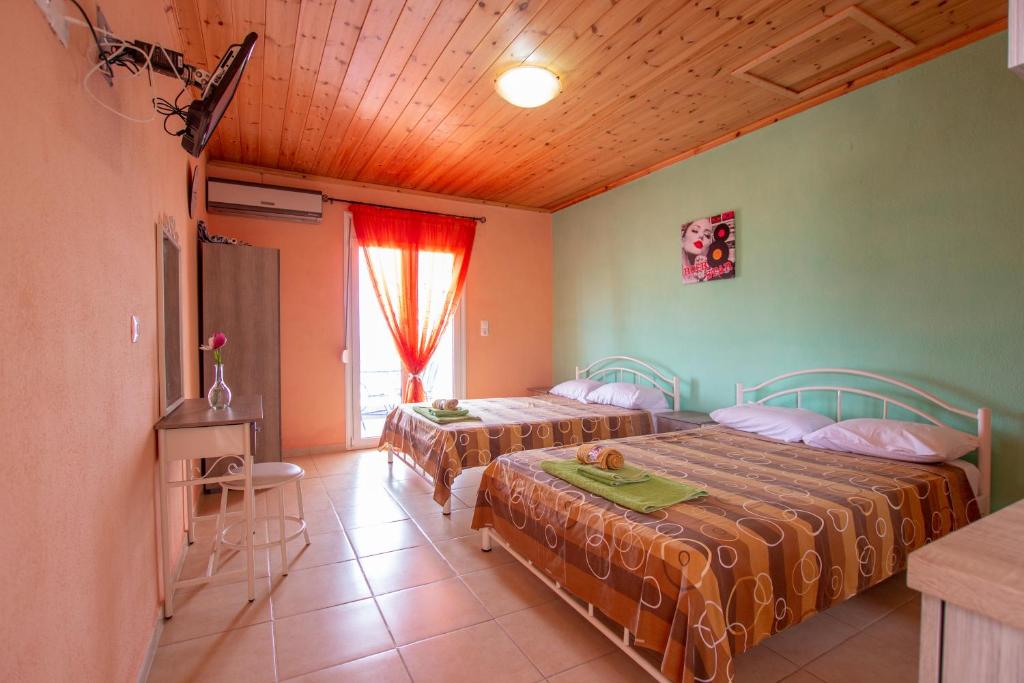a bedroom with two beds and a window at Studios ORAMA in Nea Vrasna