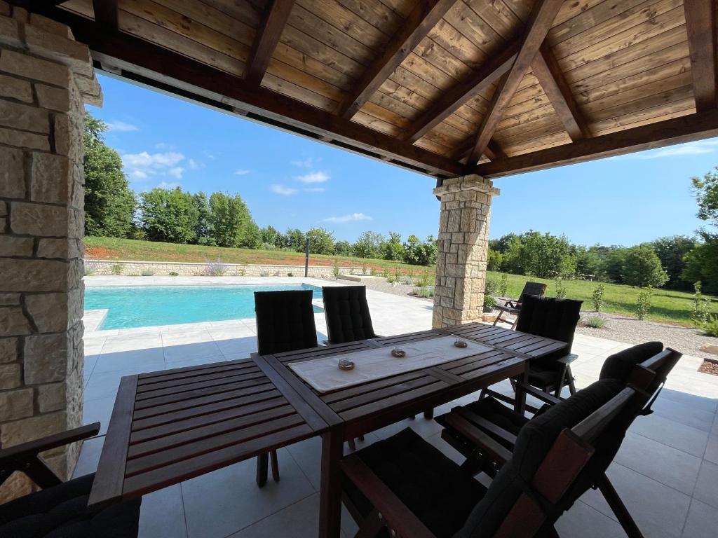 a wooden table and chairs on a patio with a pool at VILLA BERTO in Nedeščina