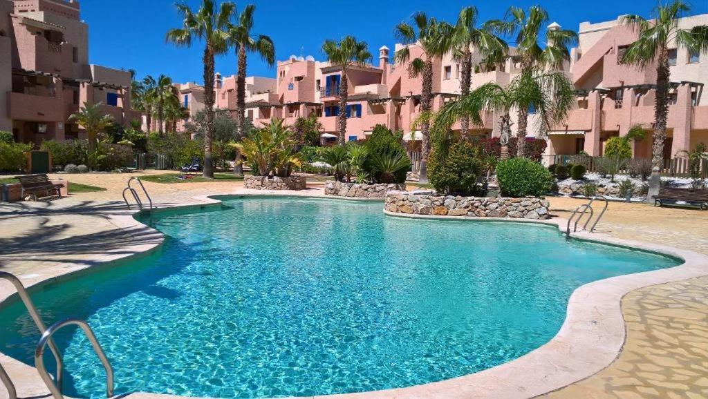 una piscina en un complejo con palmeras y edificios en Apto. urbanización privada con piscina Vera Playa, en Playas de Vera