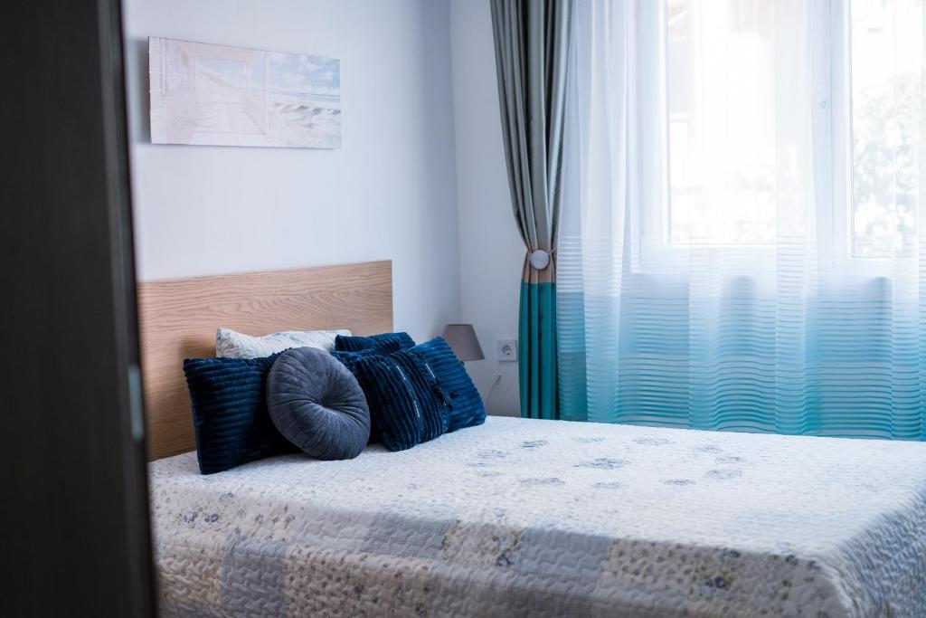een slaapkamer met een bed met blauwe kussens en een raam bij Black Sea Top Centre Apartments in Varna