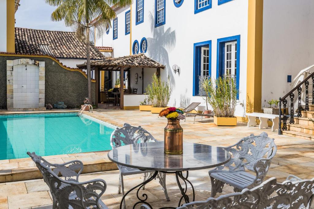 a patio with a table and chairs next to a pool at Pousada Casarão in São João del Rei