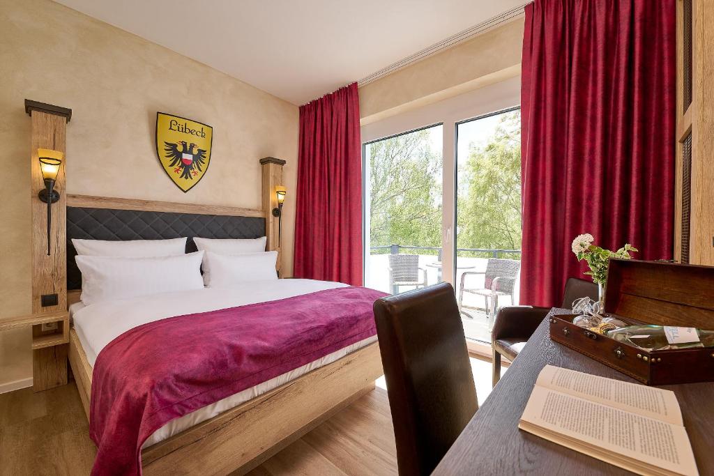 a bedroom with a large bed with red curtains at R&R Hotel Störtebeker in Baabe