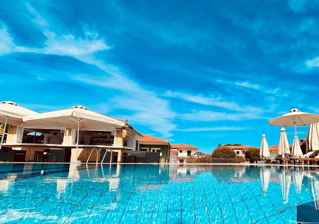 uma piscina com guarda-sóis e um céu azul em Stomio Villague em Filiatrá