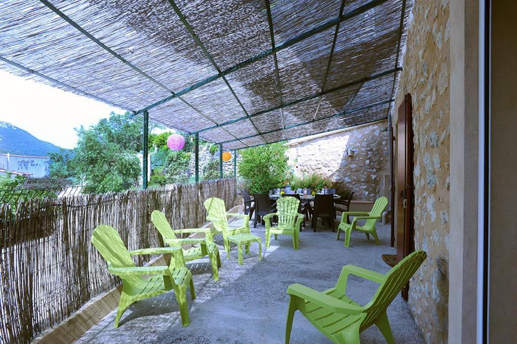 un patio con sillas y mesas verdes y una valla en Cécile en Montgaillard