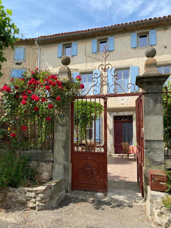 een ingang naar een huis met een poort met rode rozen bij Le Relais d'Affiac in Peyriac-Minervois