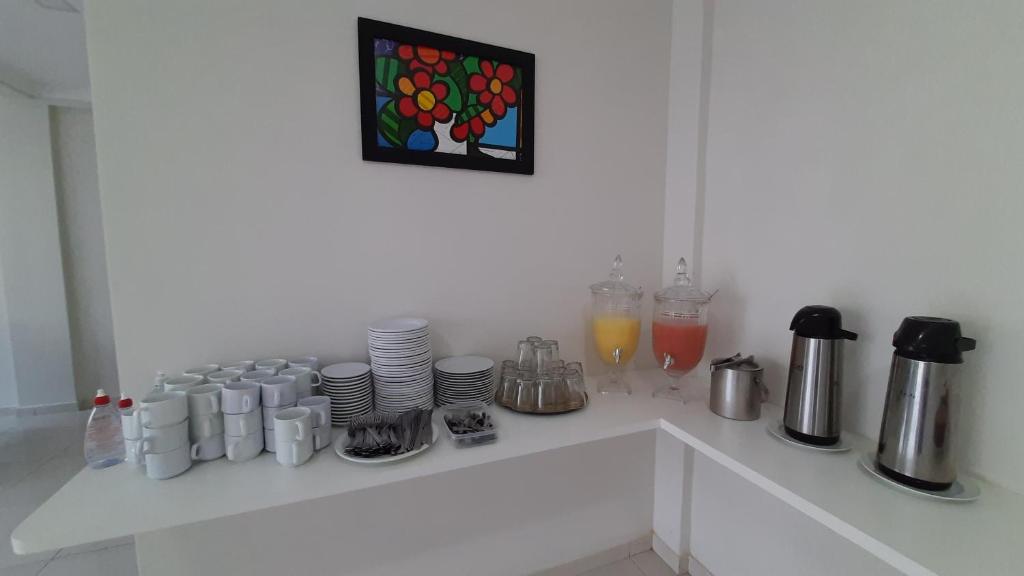 a white counter with cups and plates and drinks at Pousada Brilho dos Lençóis in Barreirinhas