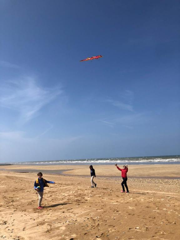 three people on a beach flying a kite at La plage au bout du jardin &#47; Sword Beach cottage in Hermanville-sur-Mer