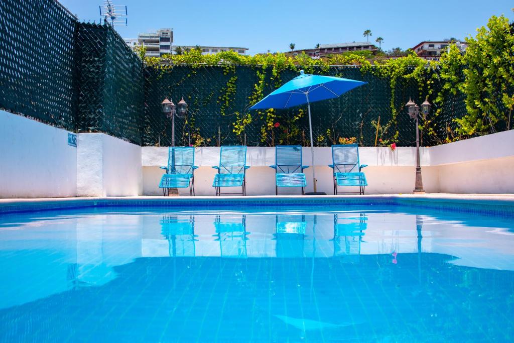 una piscina con sillas y sombrilla en Acapulco Amor en Acapulco