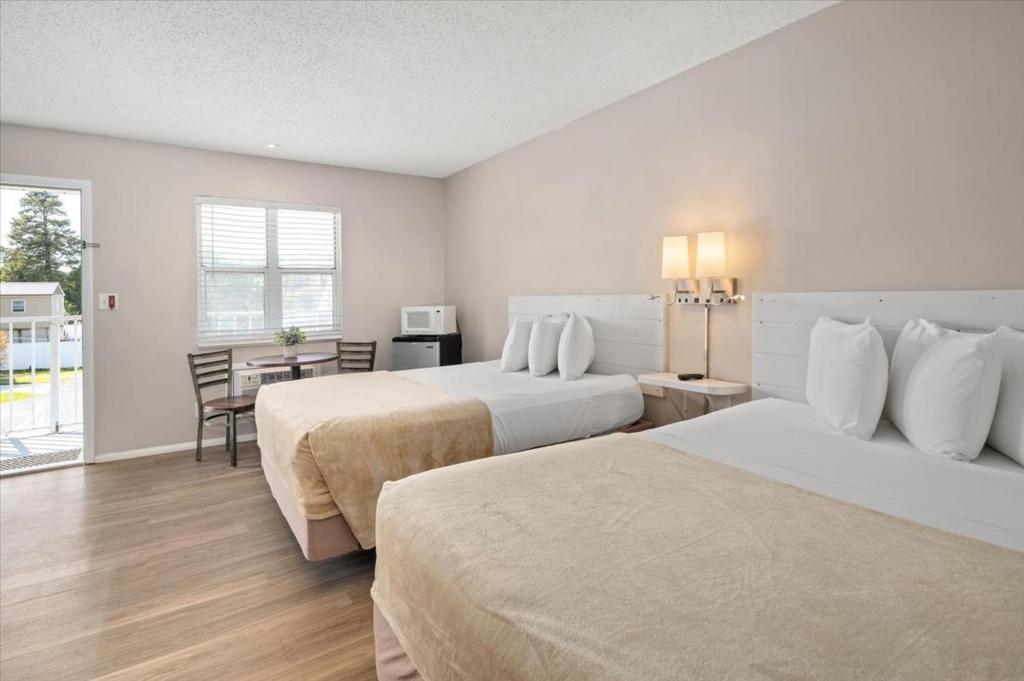 ein Hotelzimmer mit zwei Betten und einem Tisch in der Unterkunft Beach Bum West-O Motel in Ocean City