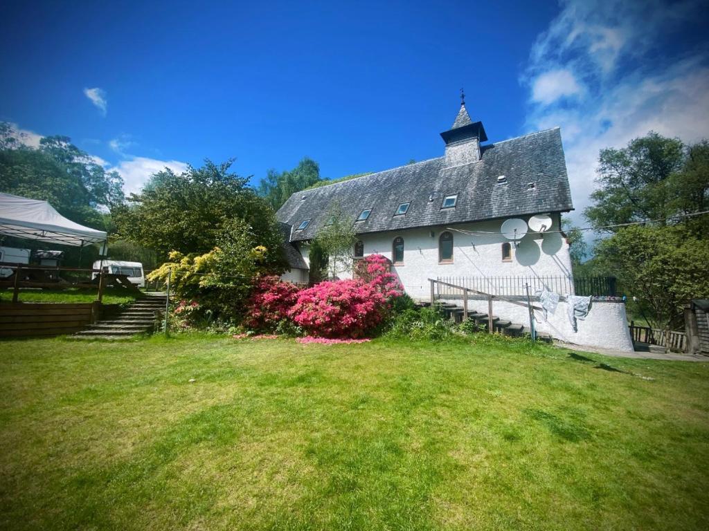 a large white house with a clock tower in a yard at Inversnaid Bunkhouse in Inversnaid